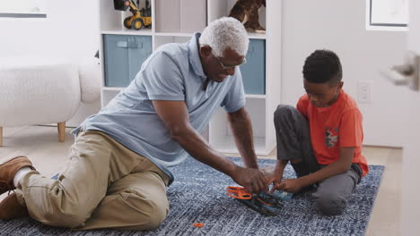 Großvater-Und-Enkel-Sitzen-Zu-Hause-Auf-Einem-Teppich-Und-Bauen-Gemeinsam-Einen-Modellhubschrauber