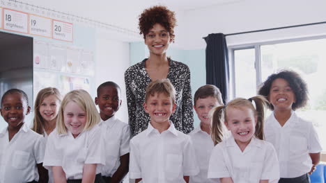Portrait-Of-Elementary-School-Pupils-Wearing-Uniform-In-Classroom-With-Male-Teacher