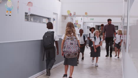 Teacher-And-Pupils-Walking-Along-Corridor-In-Busy-Elementary-School-Corridor