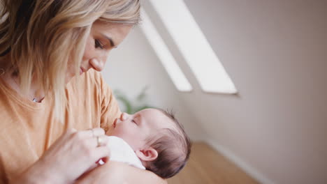 Loving-Mother-Holding-Sleeping-Newborn-Baby-Son-At-Home-In-Loft-Apartment