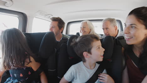 Mehrgenerationenfamilie-Sitzt-Auf-Dem-Rücksitz-Eines-Kleintransporters-Und-Wird-In-Den-Urlaub-Gefahren