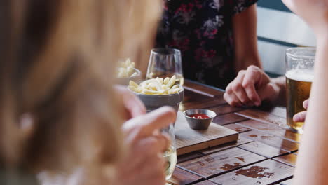 Close-Up-Of-Friends-Eating-Fries-As-They-Meet-In-Restaurant-Bar