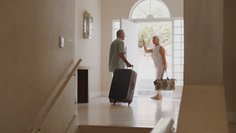 Senior-Couple-With-Suitcase-Opening-Front-Door-And-Leaving-For-Vacation