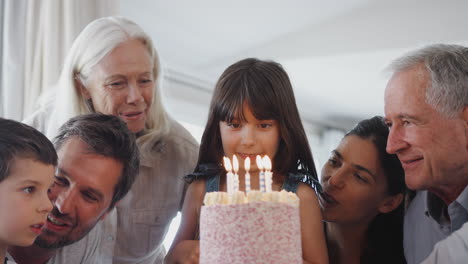 Multi-Generation-Family-Celebrating-Birthday-With-Granddaughter-At-Home-As-She-Blows-Out-Candles