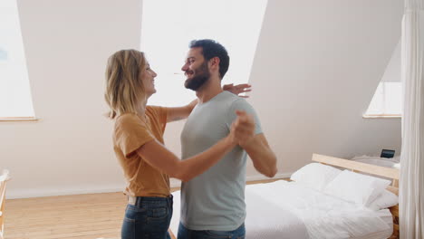 Young-Couple-Having-Fun-In-New-Home-Dancing-Together