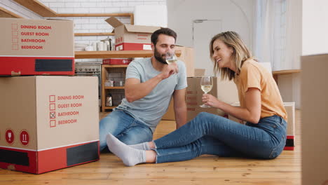 Couple-Celebrating-Moving-Into-New-Home-Making-A-Toast-With-Wine