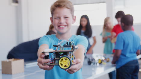 Portrait-Of-Male-Student-Holding-Robot-Vehicle-In-After-School-Computer-Coding-Class