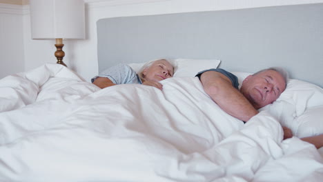 Sleeping-Senior-Couple-Lying-In-Bed-At-Home-Together