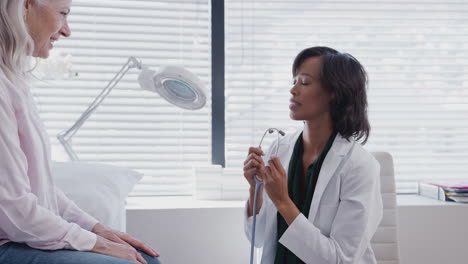 Doctor-Escuchando-A-Una-Paciente-Madura-Respirando-Con-Estetoscopio-Durante-El-Examen-Médico-En-El-Consultorio