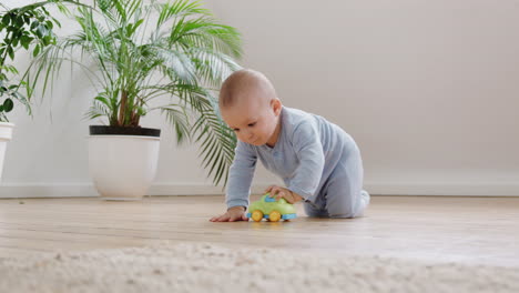 Curious-Baby-Boy-Playing-With-Toys-On-Floor-At-Home-Crawls-Towards-And-Looks-At-Camera