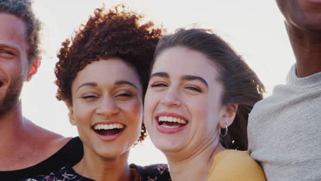 Head-And-Shoulders-Portrait-Of-Smiling-Young-Friends-Outdoors-Together-Against-Flaring-Sun