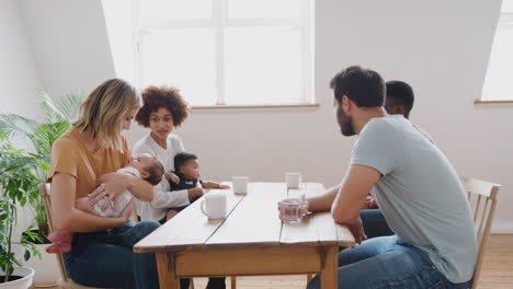 Zwei-Familien-Mit-Babys-Treffen-Sich-Und-Reden-Am-Tisch-Beim-Spieltermin-Zu-Hause