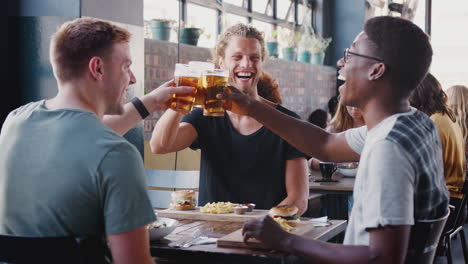 Three-Young-Male-Friends-Meeting-For-Drinks-And-Food-Making-A-Toast-In-Restaurant