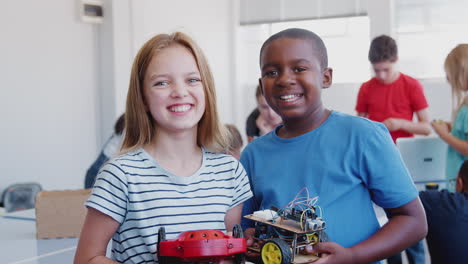 Portrait-Of-Male-And-Female-Students-Holding-Robot-Vehicle-In-After-School-Computer-Coding-Class