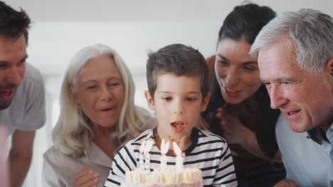 Mehrgenerationenfamilie-Feiert-Geburtstag-Mit-Enkel-Zu-Hause,-Während-Er-Kerzen-Ausbläst