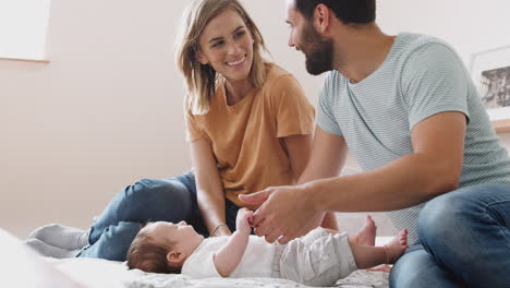 Liebevolle-Eltern-Mit-Neugeborenem-Baby,-Das-Zu-Hause-In-Der-Loft-Wohnung-Auf-Dem-Bett-Liegt