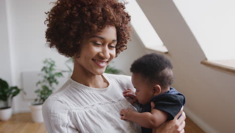 Portrait-Of-Loving-Mother-Holding-Newborn-Baby-Son-At-Home-In-Loft-Apartment