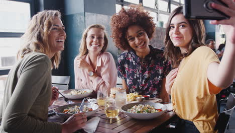 Four-Female-Friends-Posing-For-Selfie-In-Restaurant-Before-Eating-Meal