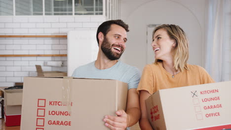 Portrait-Of-Smiling-Young-Couple-Carrying-Boxes-Into-New-Home-On-Moving-Day