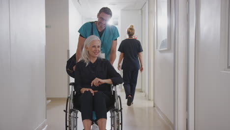 Männlicher-Pfleger-Schiebt-ältere-Patientin,-Die-Im-Rollstuhl-Aus-Dem-Krankenhaus-Entlassen-Wird