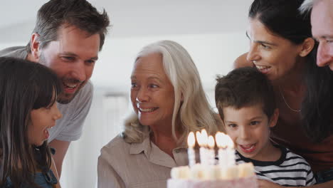Familia-Multigeneracional-Celebrando-Su-Cumpleaños-Con-Su-Nieto-En-Casa-Mientras-Apaga-Velas