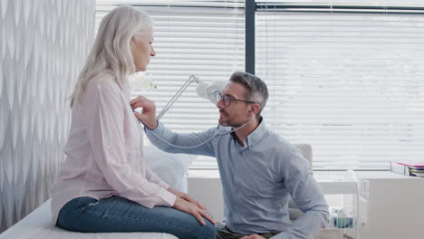Doctor-Listening-To-Mature-Female-Patient-Breathing-With-Stethoscope-During-Medical-Exam-In-Office