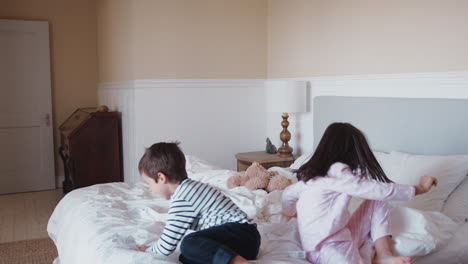 Children-Having-Fun-Jumping-And-Playing-On-Parents-Bed-At-Home