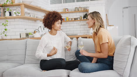 Two-Female-Friends-Relaxing-On-Sofa-At-Home-With-Glass-Of-Wine-Talking-Together