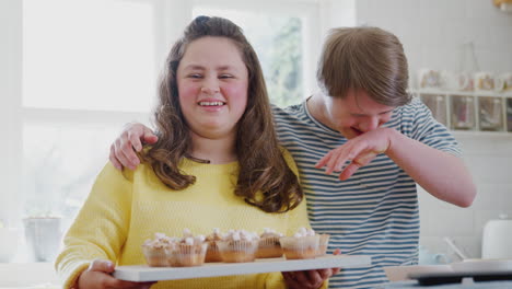 Portrait-Of-Downs-Syndrome-Couple-Holding-Homemade-Cupcakes-With-Marshmallows-In-Kitchen-At-Home