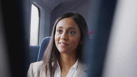 Businesswoman-And-Businessman-Commuting-To-Work-Talking-In-Train-Carriage