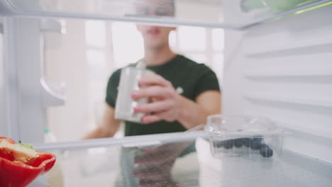 Young-Man-Looking-Inside-Refrigerator-Empty-Except-For-Open-Tin-Can-On-Shelf