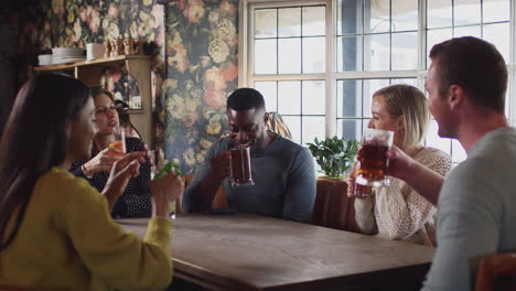 Group-Of-Friends-Making-Toast-As-They-Meet-For-Lunchtime-Drinks-In-Traditional-English-Pub