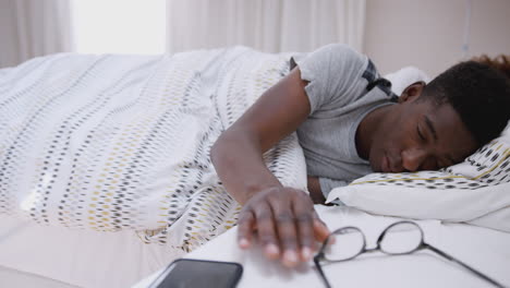 Man-Asleep-In-Bed-Reaches-Out-To-Turn-Off-Alarm-On-Mobile-Phone