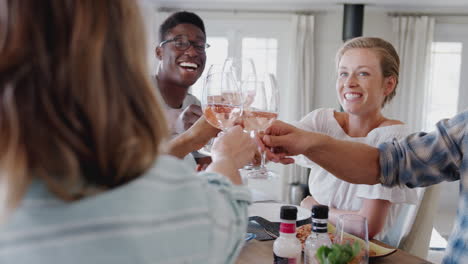 Group-Of-Young-Friends-Sitting-Around-Table-Making-A-Toast-Before-Enjoying-Meal-Together