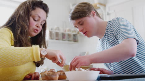 Young-Downs-Syndrome-Couple-Decorating-Homemade-Cupcakes-With-Marshmallows-In-Kitchen-At-Home