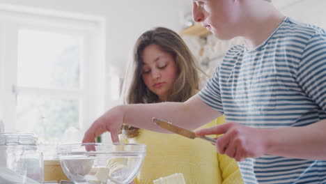Young-Downs-Syndrome-Couple-Adding-Butter-To-Cake-Recipe-They-Are-Baking-In-Kitchen-At-Home