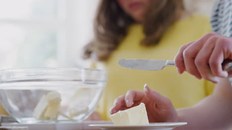 Nahaufnahme-Eines-Paares-Mit-Down-Syndrom,-Das-Butter-Zum-Kuchenrezept-Hinzufügt,-Das-Sie-Zu-Hause-In-Der-Küche-Backen