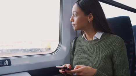 Mujer-De-Negocios-Sentada-En-El-Tren-Viajando-Al-Trabajo-Revisando-Mensajes-En-El-Teléfono-Móvil