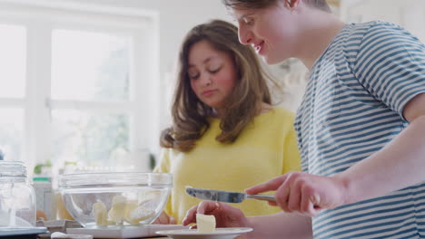 Young-Downs-Syndrome-Couple-Adding-Butter-To-Cake-Recipe-They-Are-Baking-In-Kitchen-At-Home