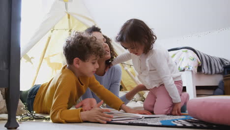 Single-Mother-Reading-With-Son-And-Daughter-In-Den-In-Bedroom-At-Home