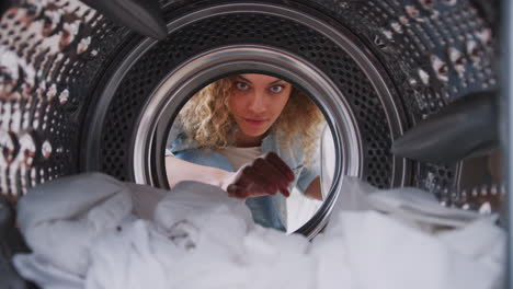 Blick-Aus-Dem-Inneren-Der-Waschmaschine,-Während-Eine-Frau-Wäsche-Herausnimmt