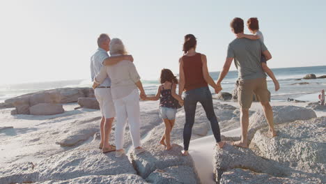Mehrgenerationenfamilie-Im-Sommerurlaub,-Die-Auf-Felsen-Steht-Und-Auf-Das-Meer-Blickt
