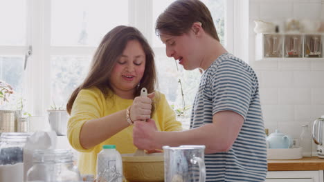 Young-Downs-Syndrome-Couple-Mixing-Ingredients-For-Cake-Recipe-They-Are-Baking-In-Kitchen-At-Home