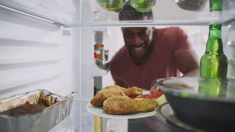 Blick-Aus-Dem-Inneren-Des-Mit-Essen-Zum-Mitnehmen-Gefüllten-Kühlschranks,-Während-Der-Mann-Die-Tür-öffnet