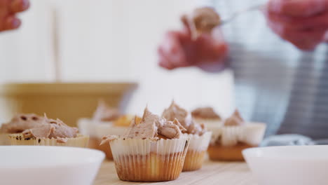 Close-Up-Of-Young-Downs-Syndrome-Couple-Decorating-Homemade-Cupcakes-With-Icing-In-Kitchen-At-Home