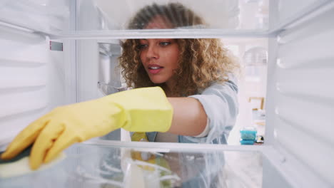 View-Looking-Out-From-Inside-Empty-Refrigerator-As-Woman-Wearing-Rubber-Gloves-Cleans-Shelves