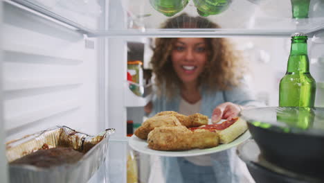 Blick-Aus-Dem-Inneren-Des-Mit-Essen-Zum-Mitnehmen-Gefüllten-Kühlschranks,-Während-Eine-Frau-Die-Tür-öffnet