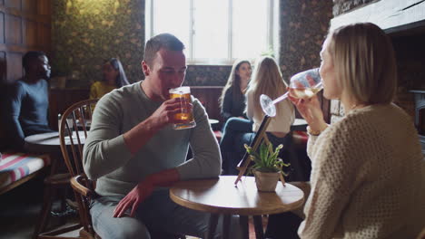 Couple-Meeting-For-Lunchtime-Drinks-In-Traditional-English-Pub-Making-A-Toast