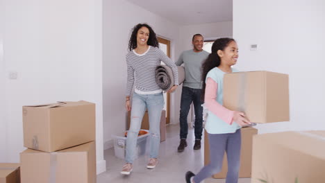 Smiling-Family-Carrying-Boxes-And-Rug-Into-New-Home-On-Moving-Day