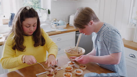 Young-Downs-Syndrome-Couple-Decorating-Homemade-Cupcakes-With-Icing-In-Kitchen-At-Home